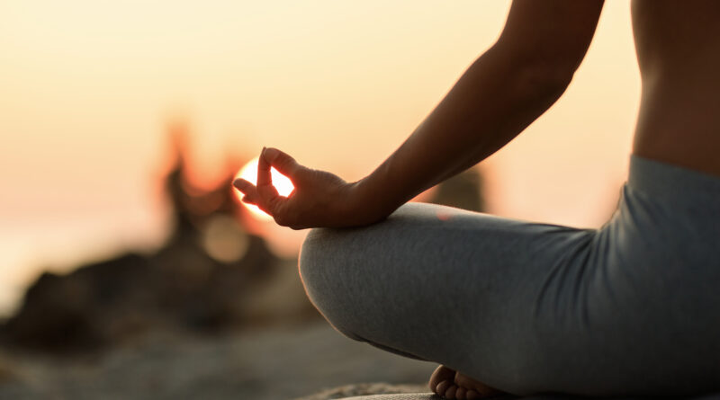 close up woman meditating lotus position sunset